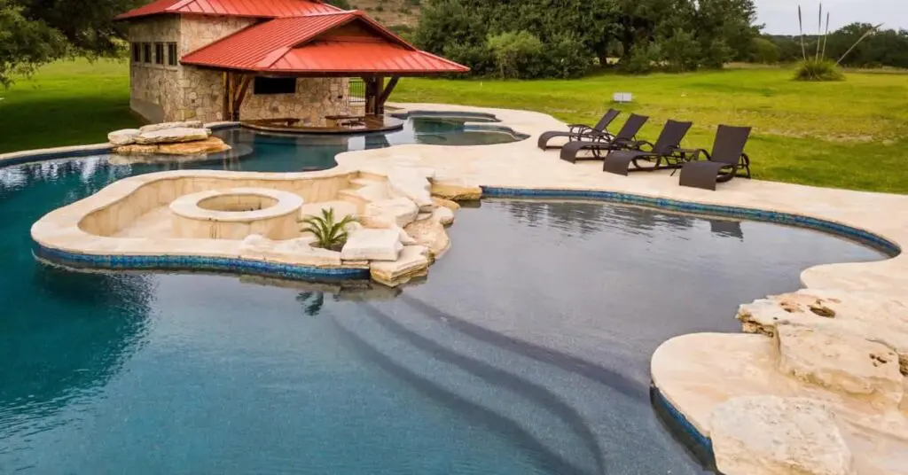 Designing A Luxurious Pool In The Diverse Austin Landscape 6 freeform pool with fire pit lounging and pool cabana in Austin Texas