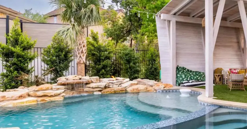 Designing A Luxurious Pool In The Diverse Austin Landscape 3 tropical style pool in Austin texas with rock waterfall and palm tree